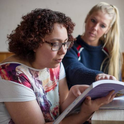 Vrouw helpt jonge vrouw met huiswerk